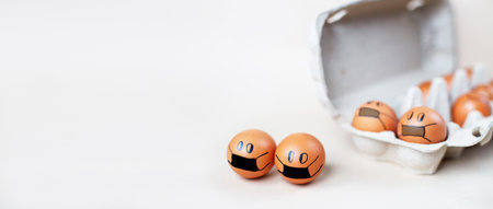 chicken eggs with drawn medical mask with egg carton on a white background. Easter eggs holidays decoration. bannerの写真素材
