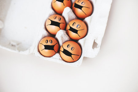 chicken eggs with drawn medical mask on egg carton on a white background. Easter eggs holidays decoration.の写真素材