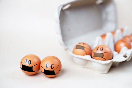 chicken eggs with drawn medical mask with egg carton on a white background. Easter eggs holidays decoration.の写真素材
