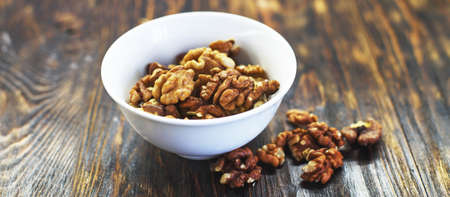 peeled walnuts in the white bowl close on brown old wooden table. healthy food concept. bannerの写真素材