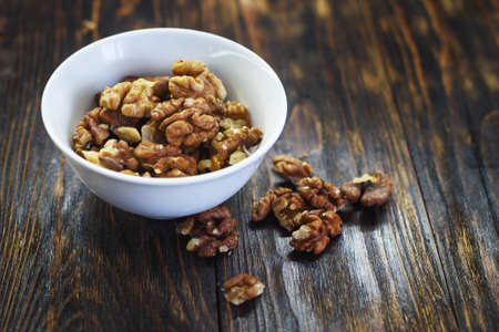 peeled walnuts in the white bowl close on brown old wooden table. healthy food conceptの写真素材