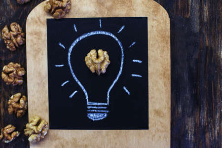 drawn light bulb with tasty shelled walnuts on a wooden backgroundの写真素材