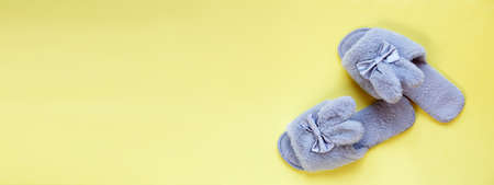 Pair of stylish soft slippers on yellow background, flat lay. copy space for your text. bannerの写真素材