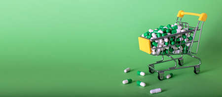 Shopping cart with medical pills on green background. bannerの写真素材