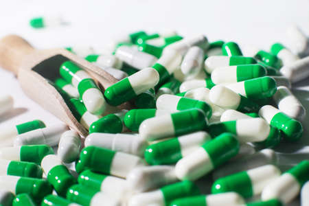 medicine green pills on white background on wooden spoon. sorted pharmaceutical