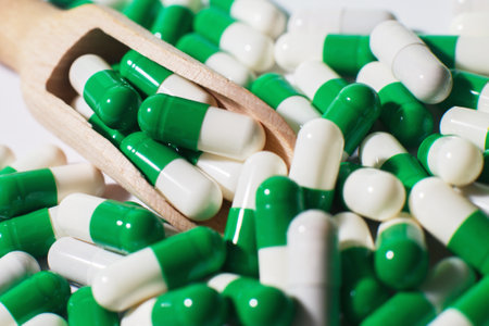medicine green pills on white background on wooden spoon. sorted pharmaceuticalの写真素材