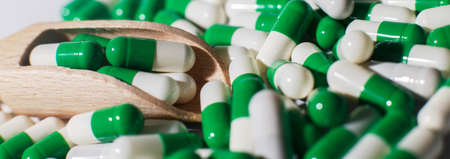 medicine green pills on white background on wooden spoon. sorted pharmaceutical. bannerの写真素材