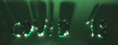 Inscription Covid 19 from letters made of pills on green background. Corona virus concept. bannerの写真素材