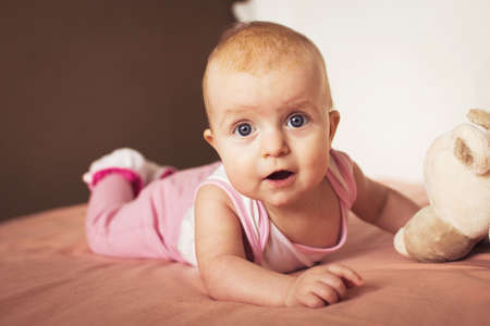 portrait of a little cute baby lying on the bed with his soft toy and smiling. crust on the baby's headの写真素材