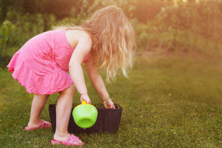 Cute little girl watering flowers in summer gardenの写真素材