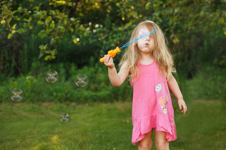 Cute little girl is blowing a soap bubblesの写真素材