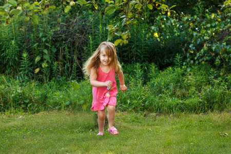 happy baby smiling. little girl running at sunset outdoorの写真素材