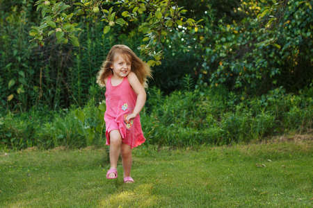 happy baby smiling. little girl running at sunset outdoorの写真素材