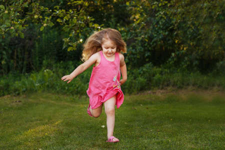 happy baby smiling. little girl running at sunset outdoorの写真素材