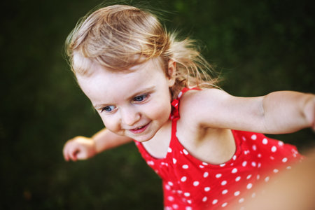 portrait of a little happy girl. the child holds the hand of a parent and playsの写真素材