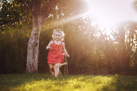 happy baby smiling. a little girl running in the garden at sunset outdoor barefootの写真素材