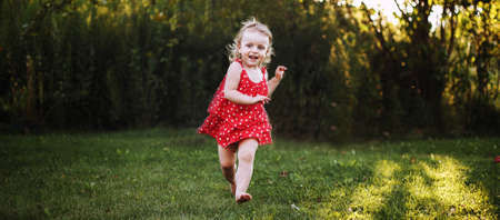 happy baby smiling. a little girl running in the garden at sunset outdoor barefootの写真素材