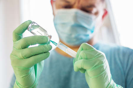 Hands of the doctor filling a syringe. Man hands in blue gloves holding vaccine. medicine, vaccination and drug concept. medicine vial dose injectionの写真素材