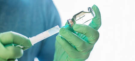 Hands of the doctor filling a syringe. Man hands in blue gloves holding vaccine. medicine, vaccination and drug concept. medicine vial dose injection. bannerの写真素材