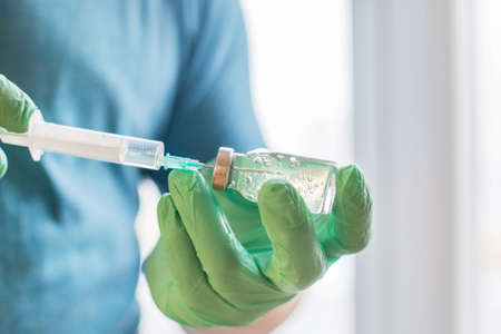 Hands of the doctor filling a syringe. Man hands in blue gloves holding vaccine. medicine, vaccination and drug concept. medicine vial dose injectionの写真素材
