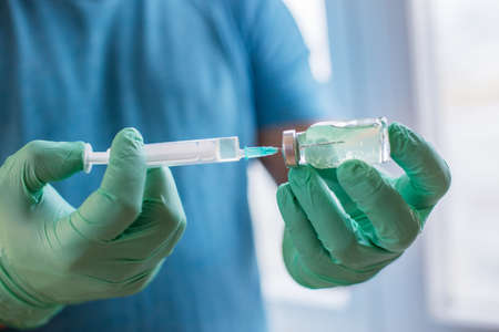 Hands of the doctor filling a syringe. Man hands in blue gloves holding vaccine. medicine, vaccination and drug concept. medicine vial dose injectionの写真素材