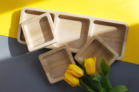 wood empty plates for snack and flowers on the color gray and yellow backgroundの写真素材