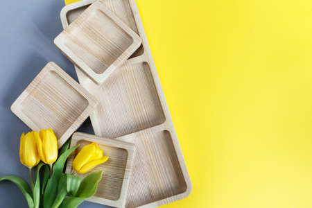 wood empty plates for snack and flowers on the color gray and yellow backgroundの写真素材