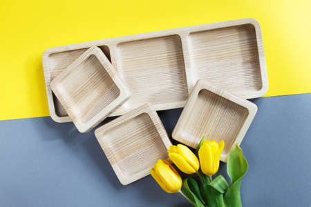 wood empty plates for snack and flowers on the color gray and yellow backgroundの写真素材