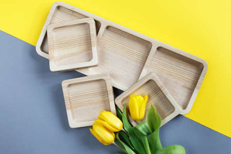 wood empty plates for snack and flowers on the color gray and yellow backgroundの写真素材