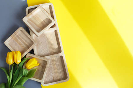 wood empty plates for snack and flowers on the color gray and yellow backgroundの写真素材