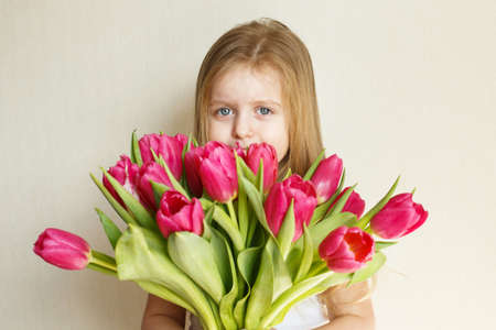 portrait of a litlle girl with bouquet of flowers tulips in her handsの写真素材