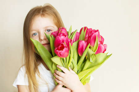 portrait of a happy smiling litlle girl with bouquet of flowers tulips in her handsの写真素材