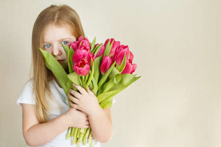 portrait of a happy smiling litlle girl with bouquet of flowers tulips in her handsの写真素材