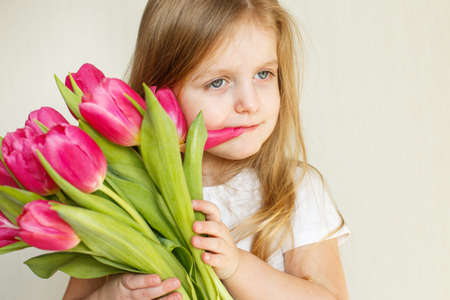 portrait of a happy smiling litlle girl with bouquet of flowers tulips in her handsの写真素材