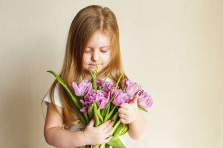 portrait of a happy smiling litlle girl with bouquet of flowers tulips in her handsの写真素材