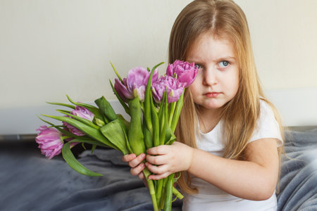portrait of a litlle girl with bouquet of flowers tulips in her handsの写真素材