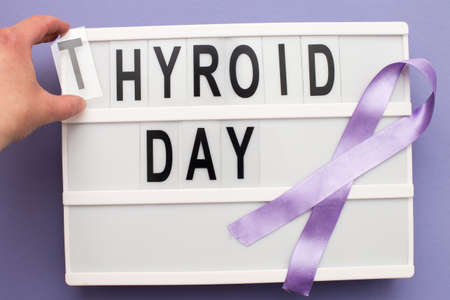 the inscription international thyroid day, violet ribbon and womans hand holding a letter on purple backgroundの写真素材