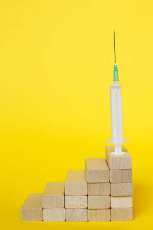 medical syringe on a ladder made of wooden sticks. drugs, vaccination conceptの写真素材