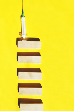 medical syringe on a ladder made of wooden sticks. drugs, vaccination concept. hard lightの写真素材