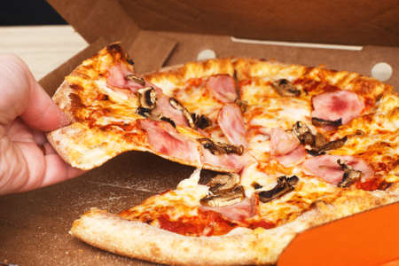 woman's hands hold pizza in a cardboard boxの写真素材