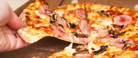 woman's hands hold pizza in a cardboard boxの写真素材
