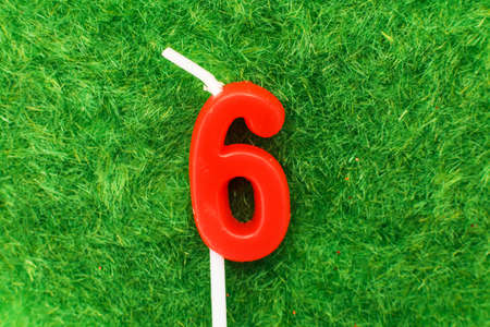candle in the form of number six on the green grass background, a place for a greeting textの写真素材