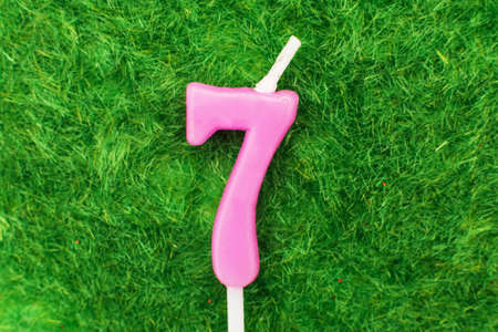 candle in the form of number seven on the green grass background, a place for a greeting textの写真素材