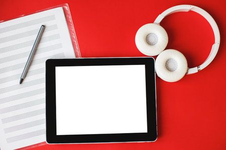 Top view open music book, headphones and a pen on a red background. mock up for a music lessonsの写真素材