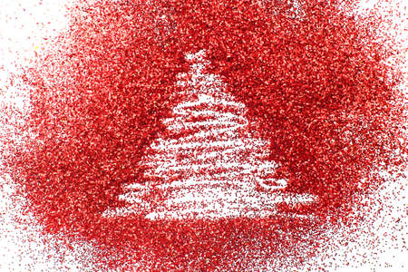 a finger drawn christmas tree on shiny red confetti backgroundの写真素材