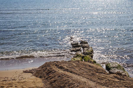 Blue water background with stones on the sandy shore. sea or ocean surface