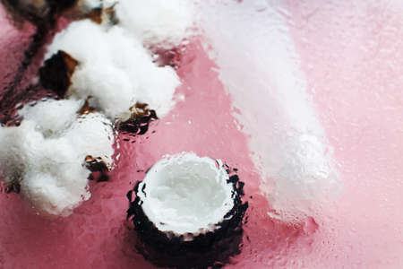 Concept of natural moisturizing skin care products. Face and hand cream under a glass surface with water on a pink background.の写真素材