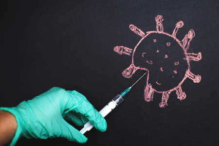 the doctor's hand makes an injection into the coronavirus molecule. The concept of defeating the virus by vaccination. vaccine against coronavirus diseaseの写真素材