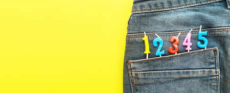 birthday candles sticking out of the back pocket of blue jeans on a yellow backgroundの写真素材