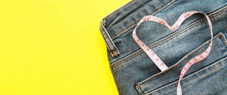 Close up of blue jeans with measure tape in the pocket in form of a heart. concept of a healthy lifestyle and diet with love to your body.bannerの写真素材